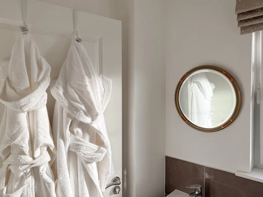 2 Egyptian cotton towelling robes hanging in guest bathroom next to the sink like a hotel