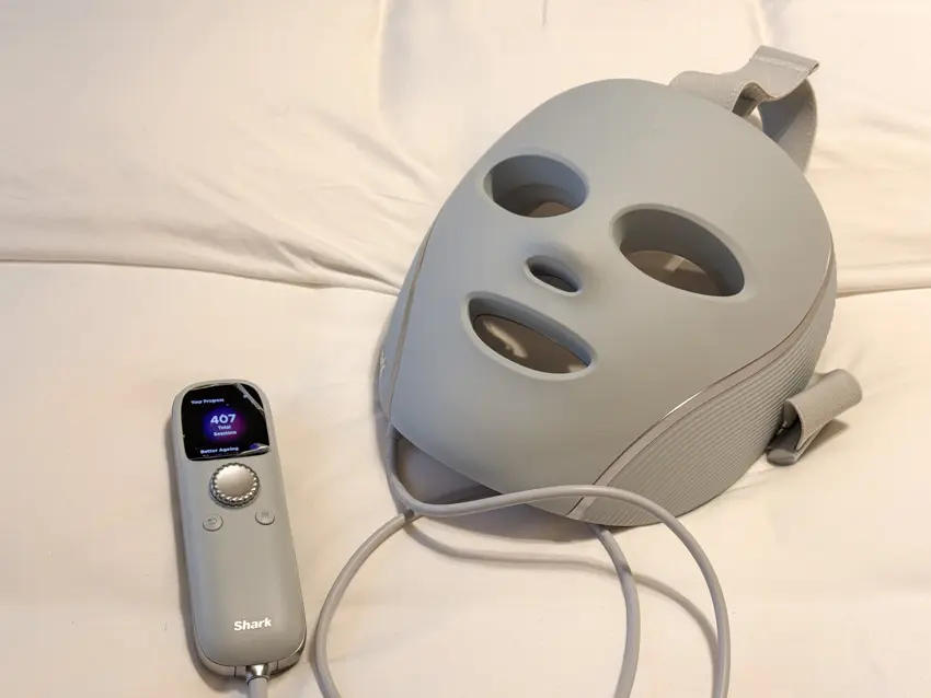 Grey Shark CryoGlow LED face mask and wired controller on white bedding, with 407 total sessions on the screen.