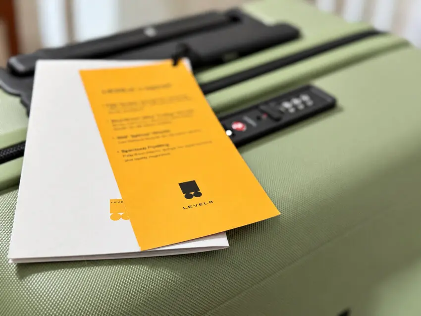 LEVEL8 booklet and orange card resting on the lid of a green carry-on suitcase