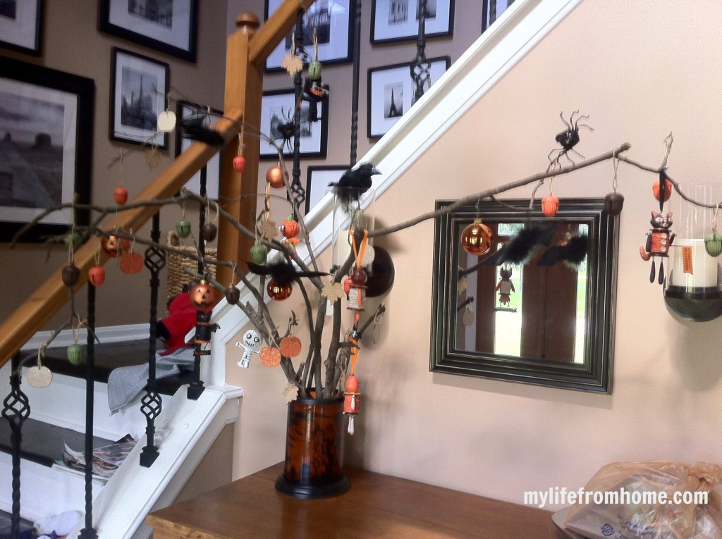 Close-up of a black cat Halloween ornament hanging on a rustic branch.