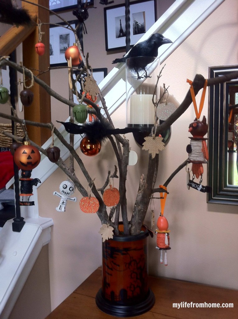 Image of the rustic Halloween tree with various ornaments hanging on branches in a vase.
