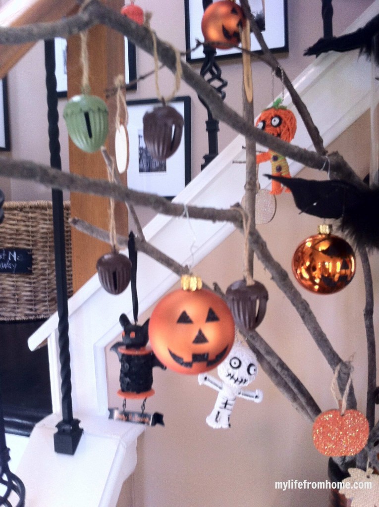 View of a pumpkin ornament and acorn ornaments on a rustic Halloween tree.