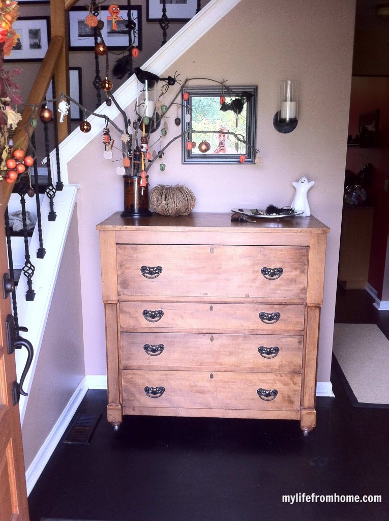 Rustic Halloween tree centerpiece on a foyer console with various ornaments.