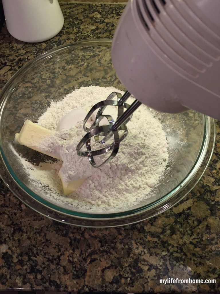 Butter and sugar in a glass mixing bowl with a hand mixer ready to cream together