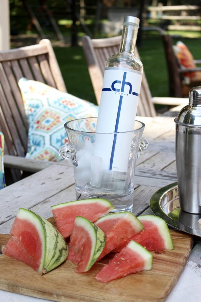 Sliced watermelon on a chopping board next to CH vodka