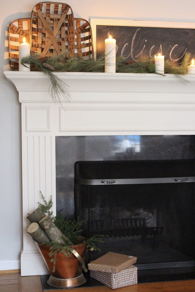 A farmhouse Christmas Mantel dressed in candlelight- home decor- holiday- mantel decor- Do it Yourself- DIY DIY projects- candlelight mantel- living room decorating ideas- room design- rustic home decor- decoration ideas- candlelight and greenery mantel- chalkboard script- winter mantel- candlelight- farmhouse Christmas ideas- decor- tobacco baskets in decor