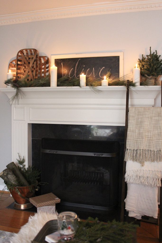 A farmhouse Christmas Mantel dressed in candlelight- home decor- holiday- mantel decor- Do it Yourself- DIY DIY projects- candlelight mantel- living room decorating ideas- room design- rustic home decor- decoration ideas- candlelight and greenery mantel- chalkboard script- winter mantel- candlelight- farmhouse Christmas ideas- decor- tobacco baskets in decor