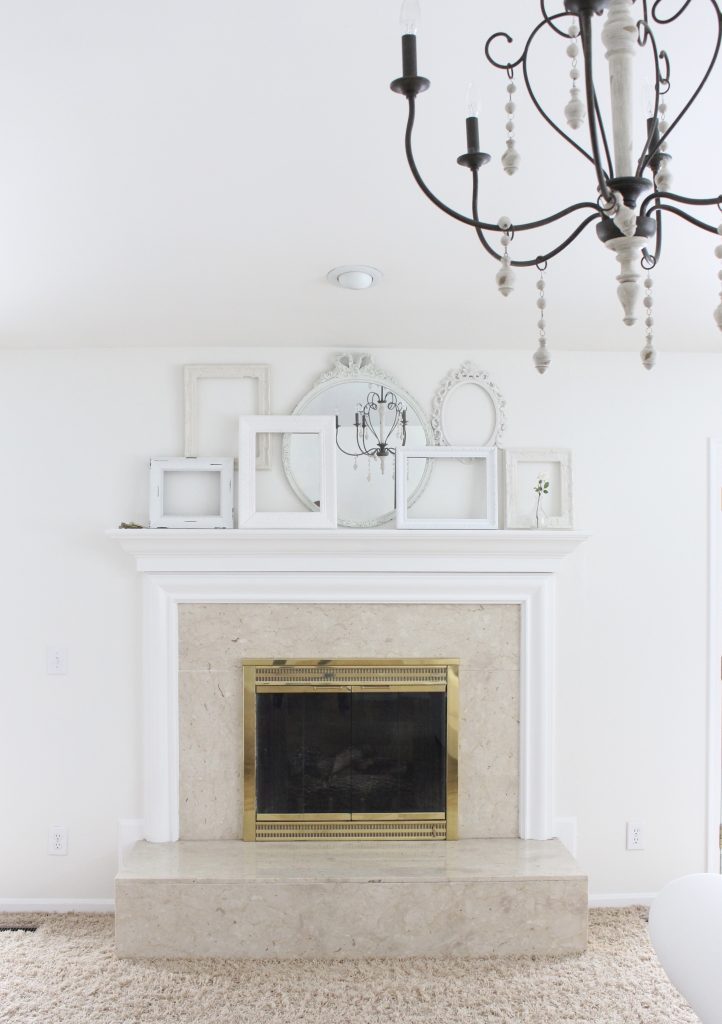 A shabby chic white mantel- layered frames- white mirror- all white decor- romantic design- fireplace decor- mantel decor- home design- decor ideas- mantles- french country style mantel- DIY- Do it Yourself- DIY projects- room design- wall decorating ideas- gallery wall- room decor ideas- decoration ideas- farmhouse style chandelier- french country chandelier