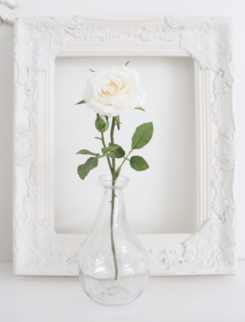 A shabby chic white mantel- layered frames- white mirror- all white decor- romantic design- fireplace decor- mantel decor- home design- decor ideas- mantles- french country style mantel- DIY- Do it Yourself- DIY projects- room design- wall decorating ideas- gallery wall- room decor ideas- decoration ideas- farmhouse style chandelier- single bloom