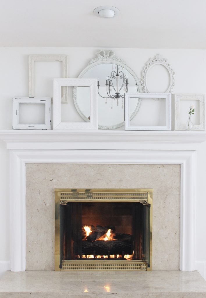 A shabby chic white mantel- layered frames- white mirror- all white decor- romantic design- fireplace decor- mantel decor- home design- decor ideas- mantles- french country style mantel- DIY- Do it Yourself- DIY projects- room design- wall decorating ideas- gallery wall- room decor ideas- decoration ideas- distressed white frames