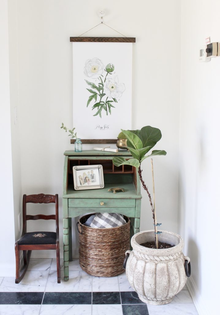 green desk- vignette- spring decor- filling a nook- fiddle fig leaf tree- brass animals- green painted furniture- vintage bottles- hanging wall canvas