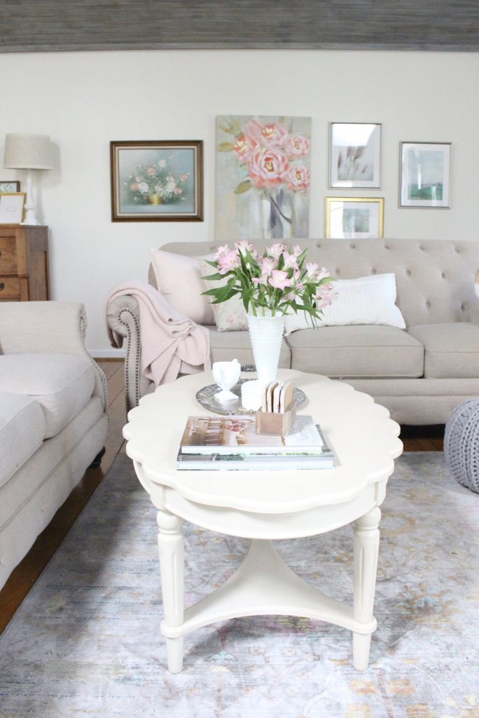 An updated family room space with seasonal spring decor, spring- family room decor- gray washed ceiling- pink decor- gray decor- using pastels in decorating- large family room space- French country coffee table- tufted couch