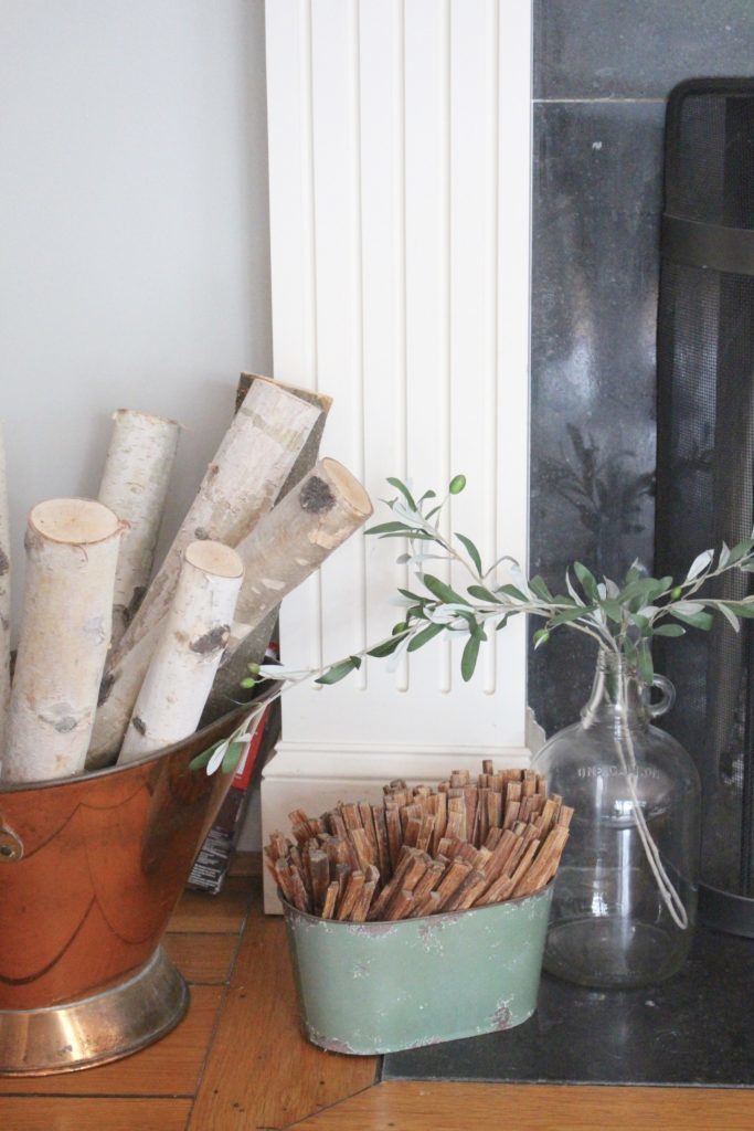 Transitional Fall Mantel- how to decorate the easy way for fall- mantel decor- mantles- decorating a fall mantel- autumn decor- decorating with wheat- pumpkins- olive branches- glass jug- copper firewood bin