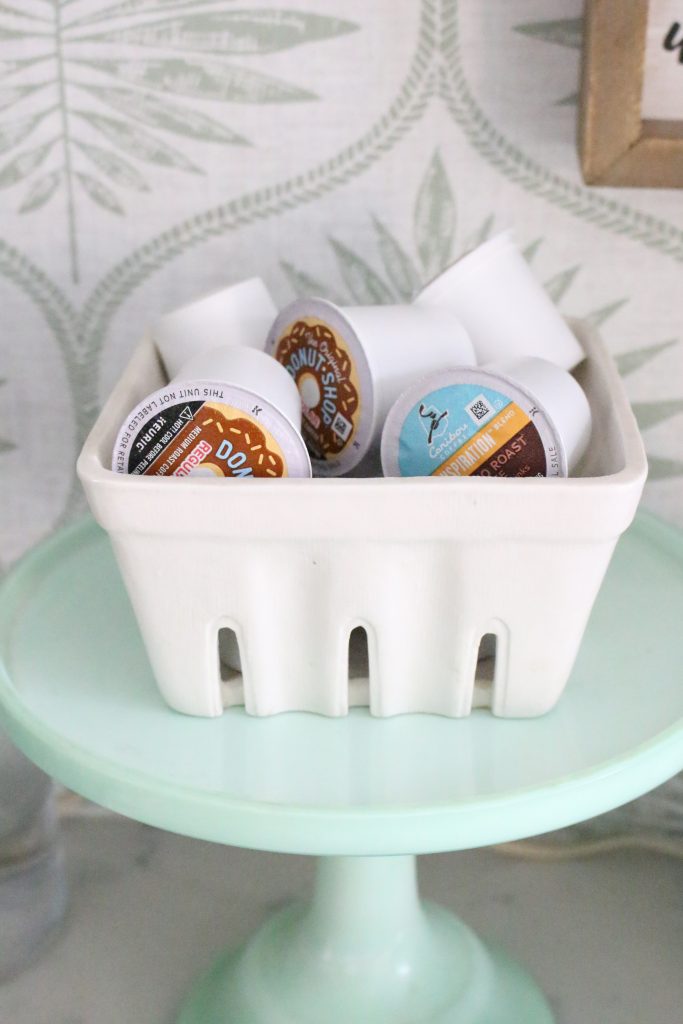 Coffee pods in a ceramic bowl on a coffee station cabinet with eye catching wallpaper behind them