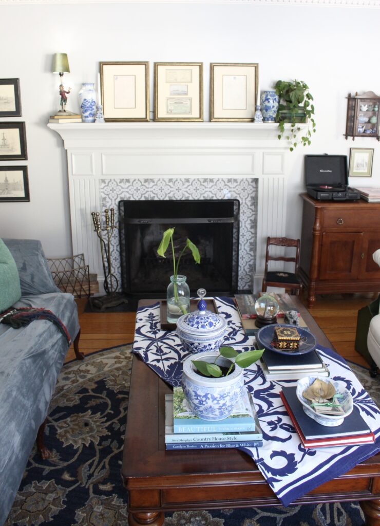 Library room seating area with fireplace, blue and white coffee table styling, record player, and navy rug