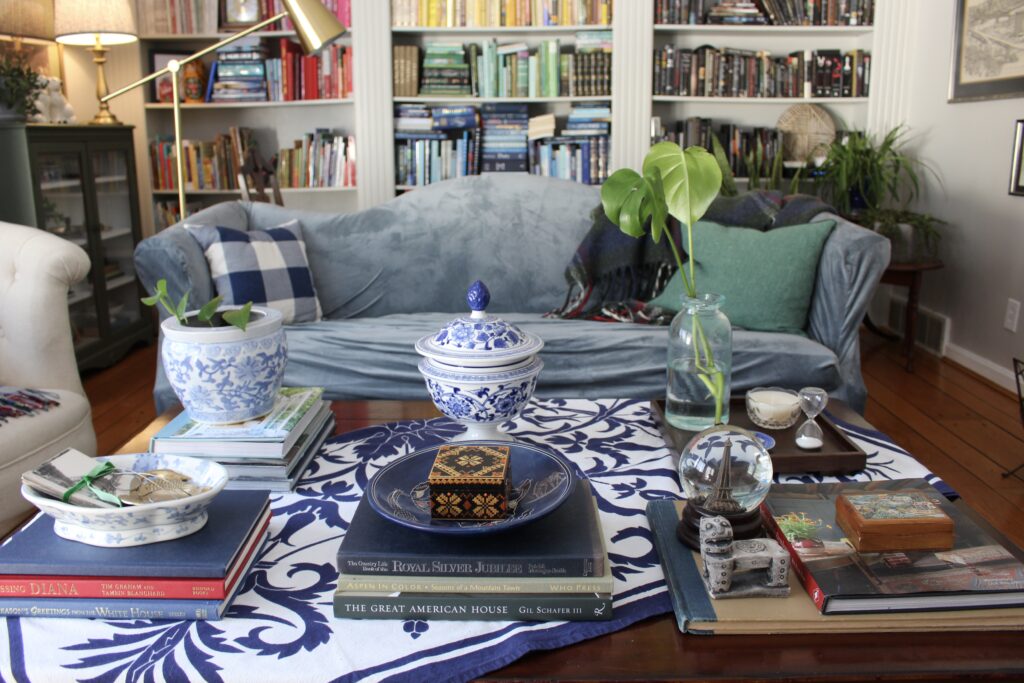 Slipcovered sofa with colourful built-in bookshelves behind and styled coffee table with blue and white runner