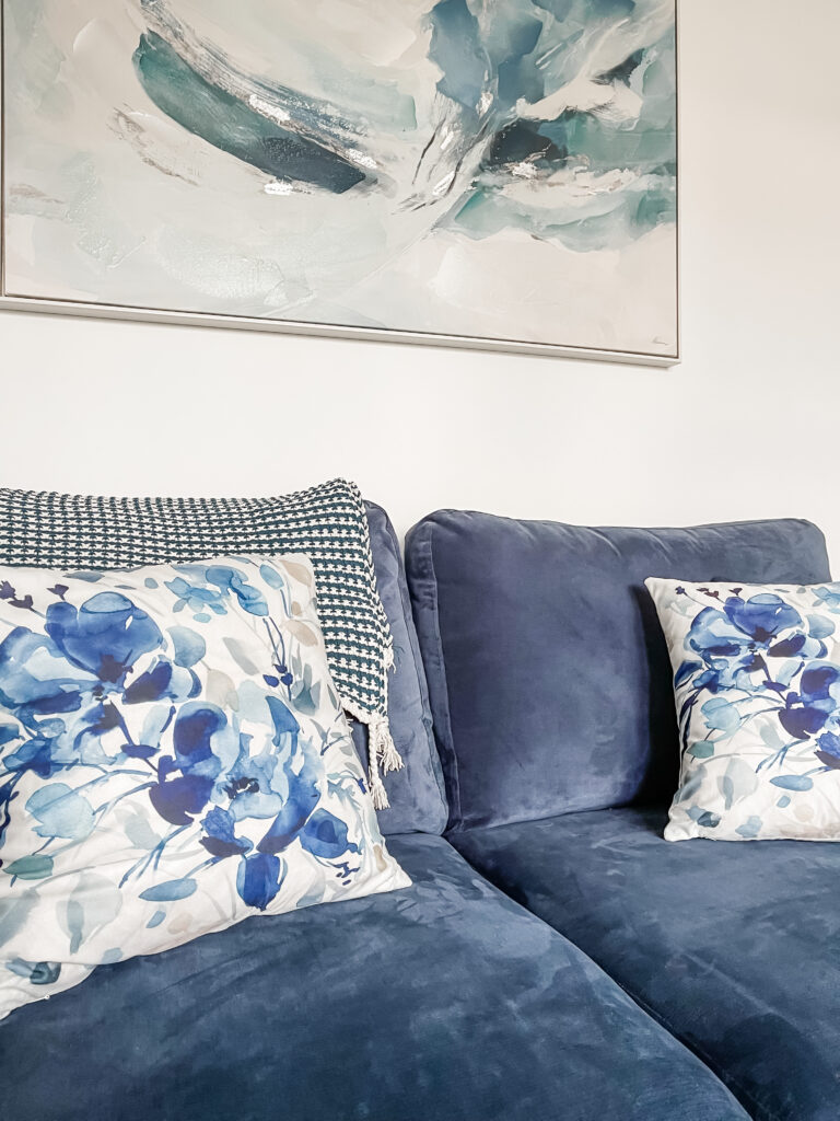 Watercolour floral cushion covers from Shein on a blue sofa with abstract art