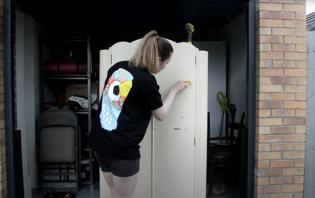 sanding down the chipped paint on the wardrobe