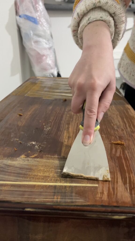 Close-up of sanding and stripping varnish from a vintage music cabinet.