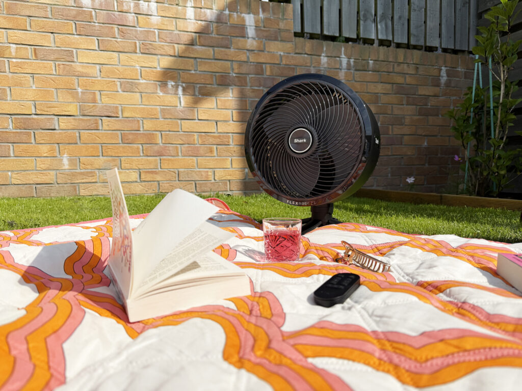 Shark FlexBreeze High-Velocity Hybrid Fan FA220UK in the compact setting blowing pages of a book on a picnic blanket