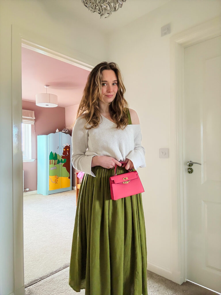 Olive green midi skirt styled with a white jumper and hot pink bag, a fun and colourful look for autumn.