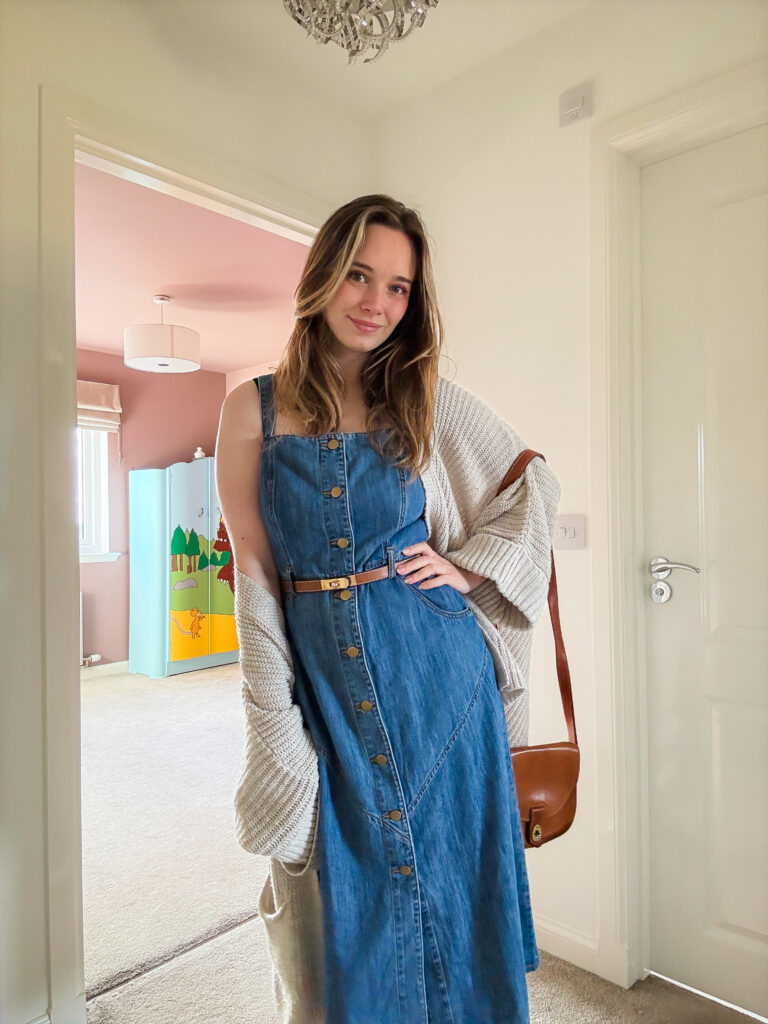 Casual autumn look with a belted denim dress, oversized cardigan, and trainers for a relaxed weekend outfit.