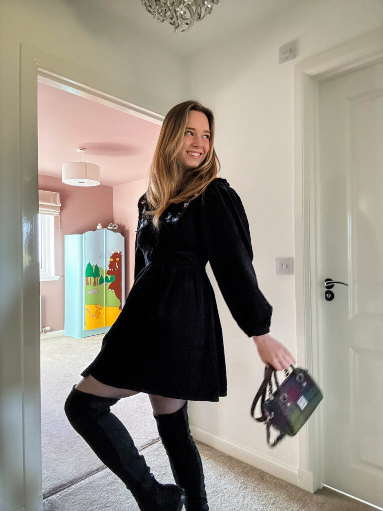Gillian wearing a black corduroy dress with a floral embroidered Peter Pan collar, styled with tights and boots for autumn.