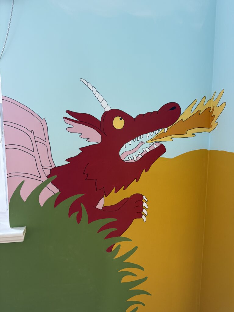 Red Room on the Broom dragon breathing fire, painted on a bedroom corner wall near a window.