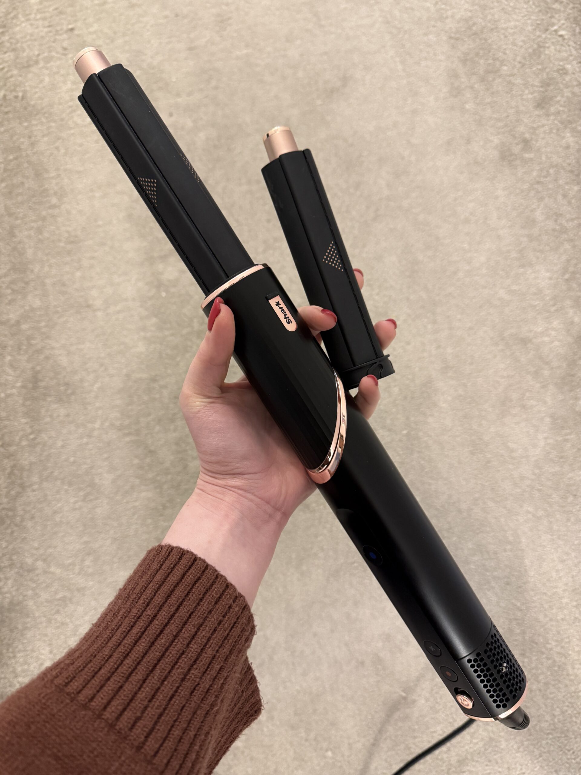 Hand holding black Shark FlexStyle with curling barrels before use.