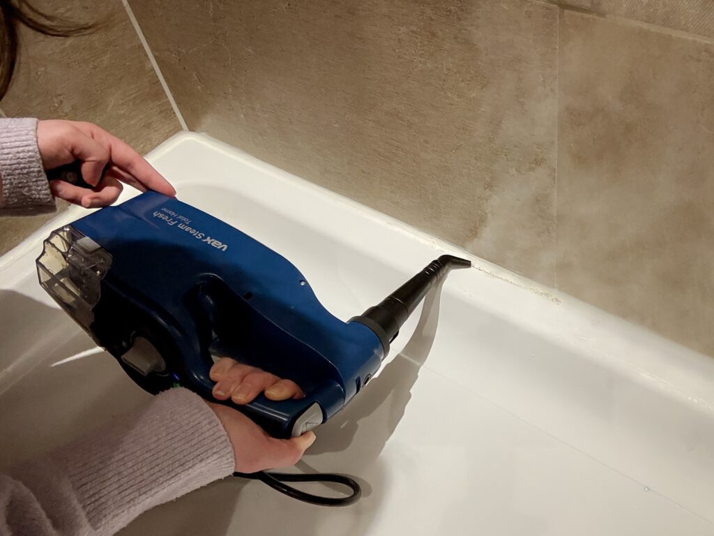 Using the Vax Steam Fresh Total Home in handheld mode to clean bathroom tiles and grout around the shower