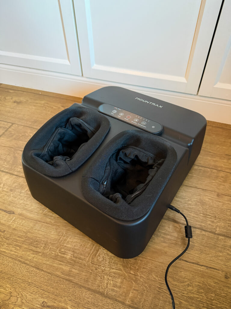 MOUNTRAX electric foot massager side view showing sleek black design and control panel on wooden floor