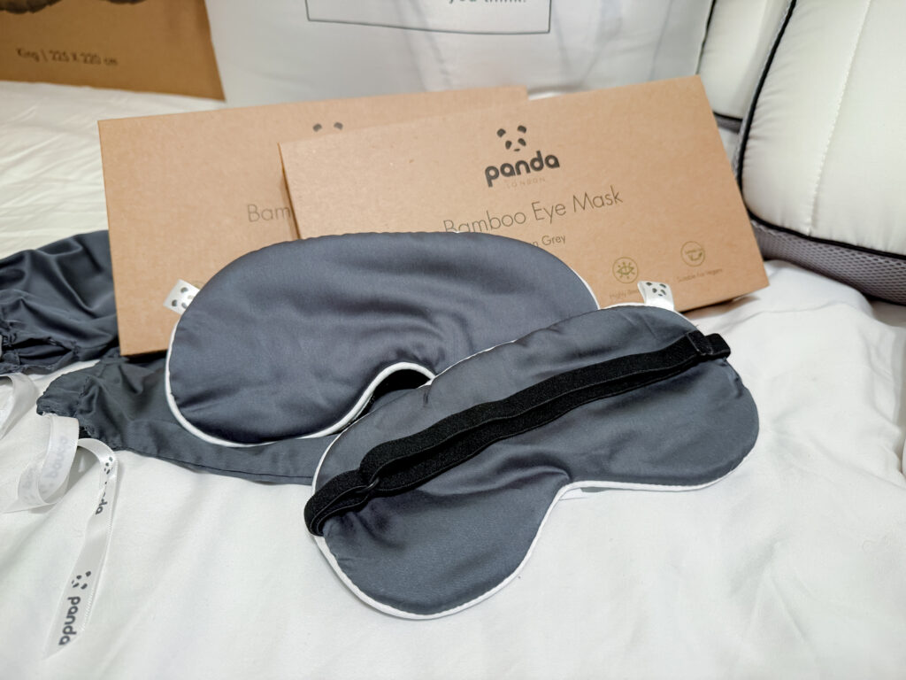 Two grey bamboo eye masks resting on white bedding, designed for a better night's sleep.