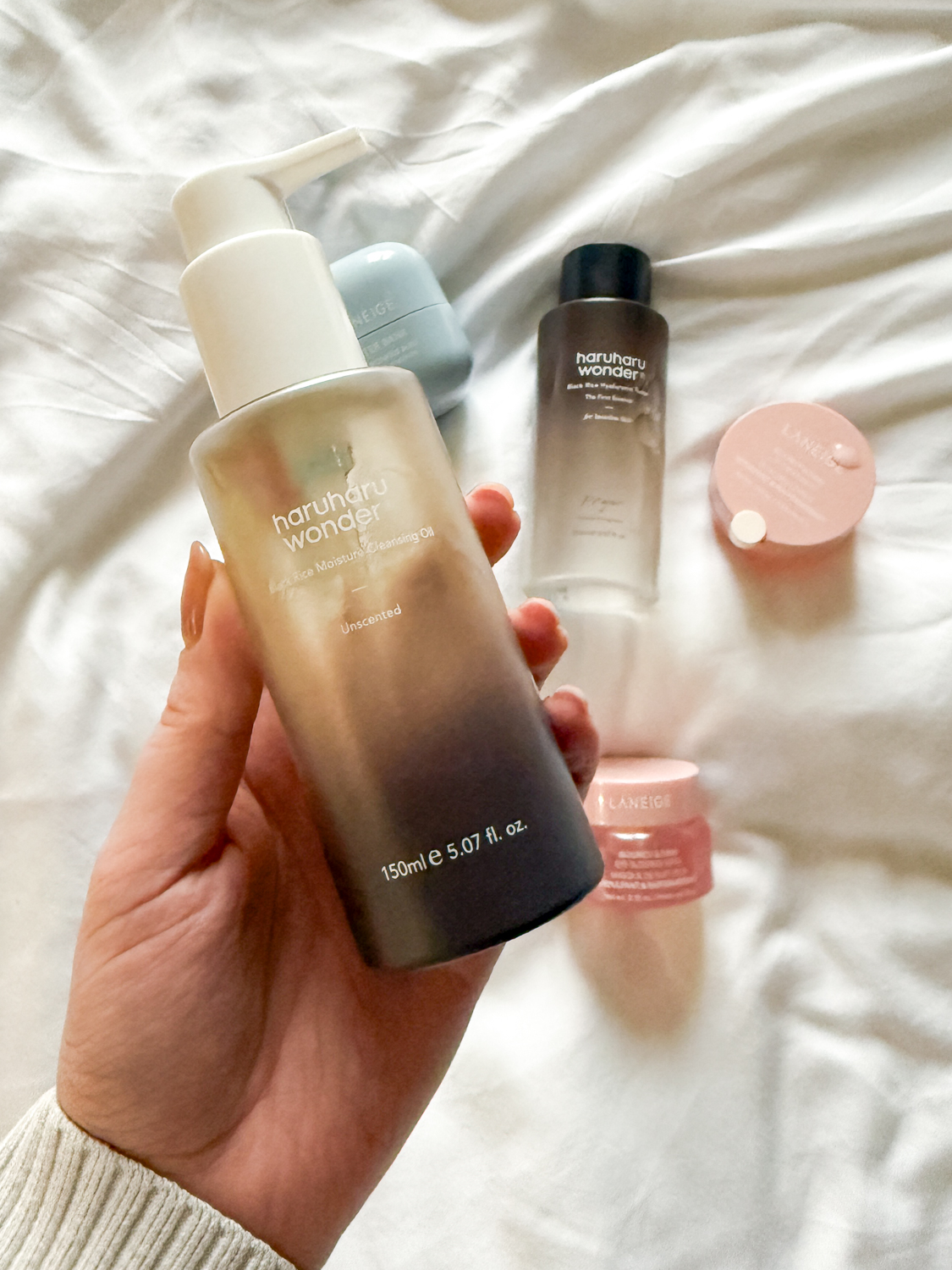Close-up of hydrating K-beauty products including Haruharu Wonder cleansing oil and Laneige sleeping mask, illustrating the shift toward gentle ingredients for achieving glass skin.