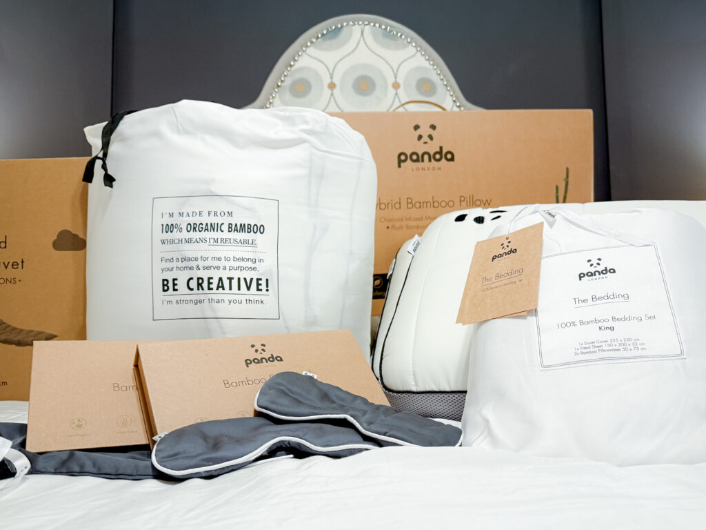 A full collection of Panda London sleep products on a bed, including the Cloud Duvet, Hybrid Pillows, Bamboo Bedding Set, and eye masks.