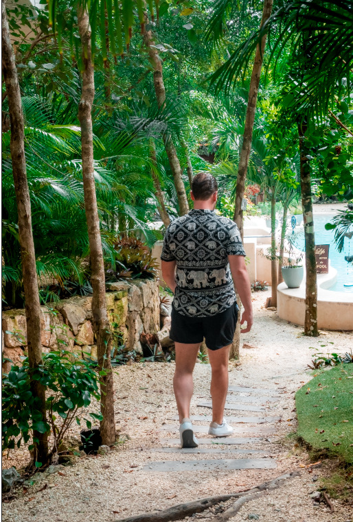 A guest walking along a shaded jungle path through the grounds of Cachito de Cielo Tulum