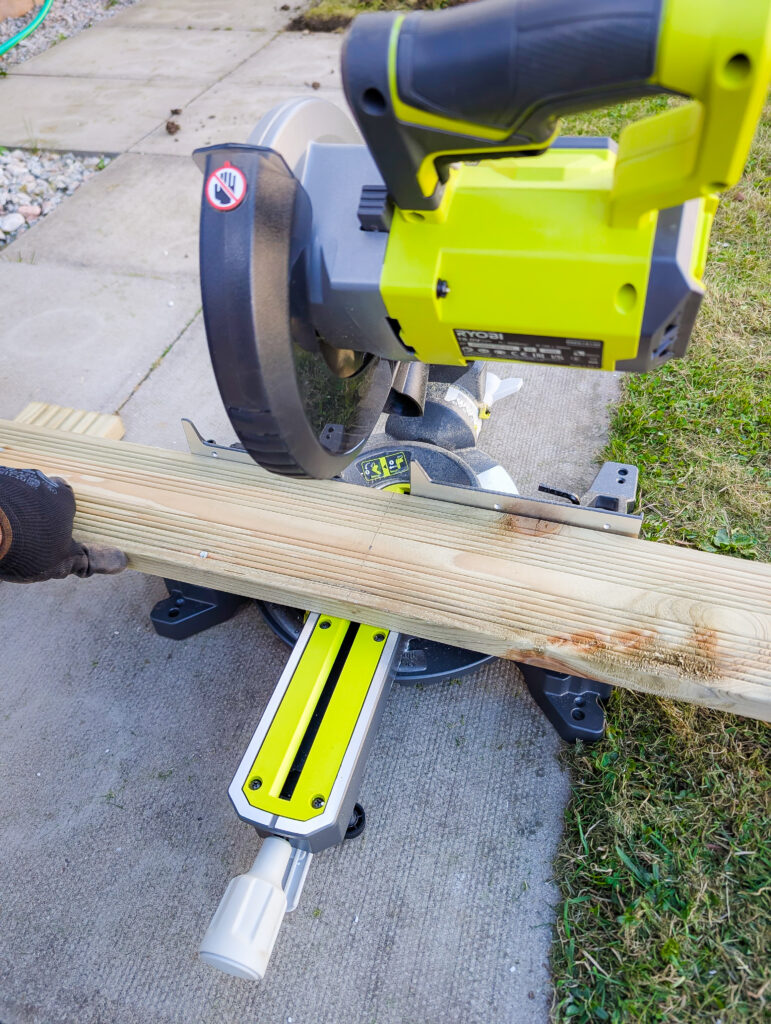 Cutting a treated decking board to size on a Ryobi cordless mitre saw