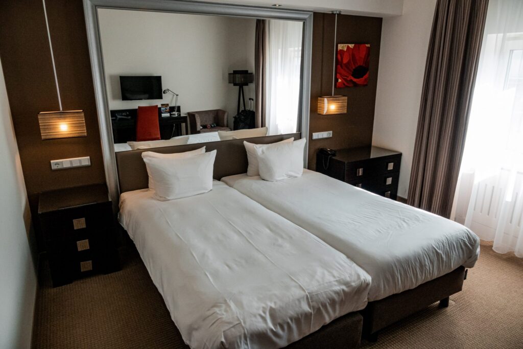 Standard hotel room at Grand Hotel Amrath Kurhaus with double bed, white linens, dark wood furniture and large wall mirror