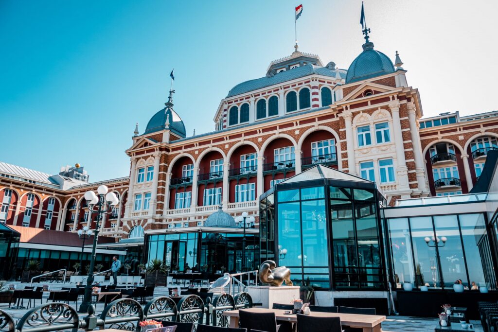 Grand Hotel Amrath Kurhaus exterior on a sunny day, showing the Victorian facade, central dome and outdoor terrace seating