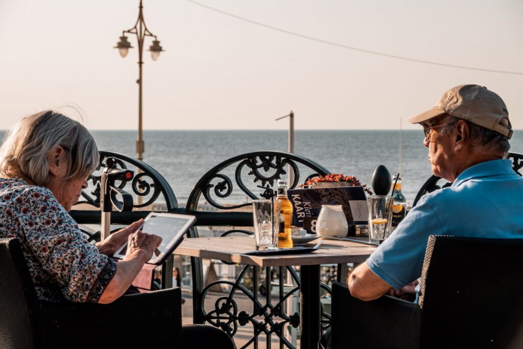 Couple enjoying drinks at an outdoor terrace table on the Scheveningen promenade with the North Sea in the background
