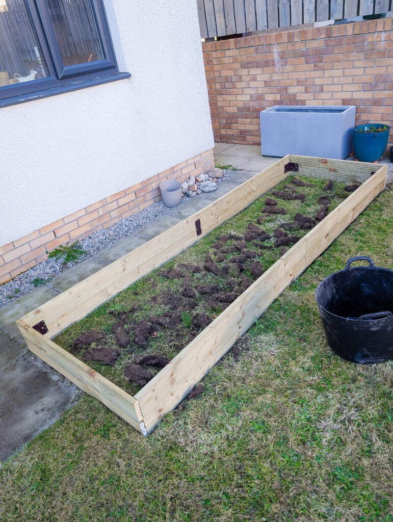 The assembled decking board frame positioned over the prepared ground with the turf dug out inside