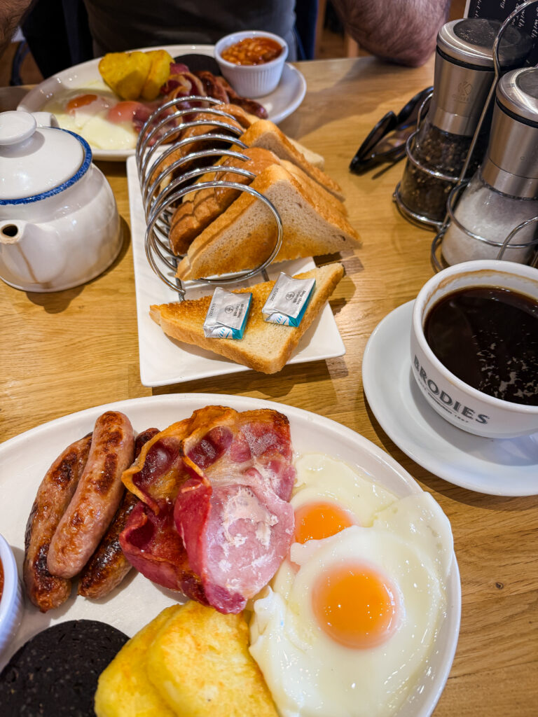 A full cooked Scottish breakfast at The Bothy in Ballater, with eggs, bacon, sausages, toast, tea, and coffee spread across the table