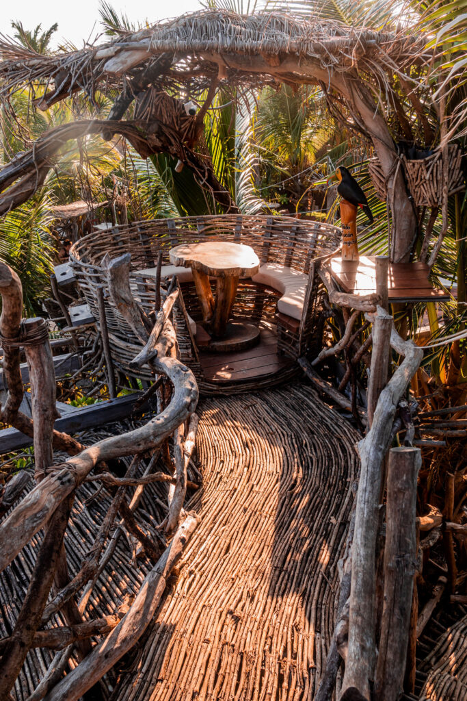 Intricate wicker seating area and walkway at a Tulum beach club surrounded by jungle