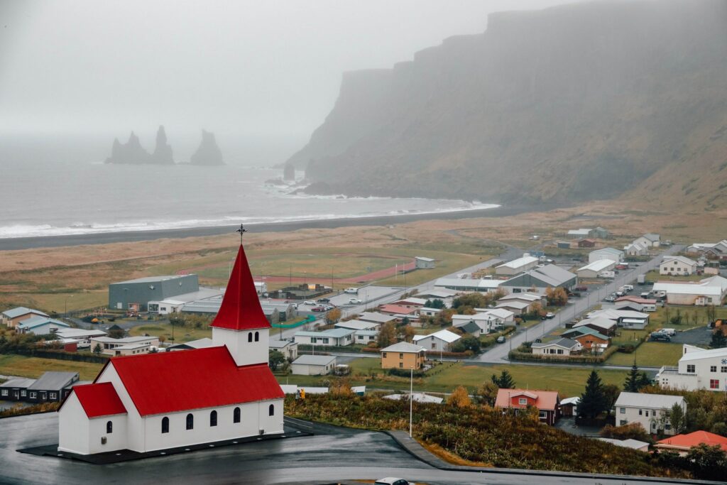 Iconic red-roofed Víkurkirkja church overlooking the village of Vík and Reynisfjara black sand beach