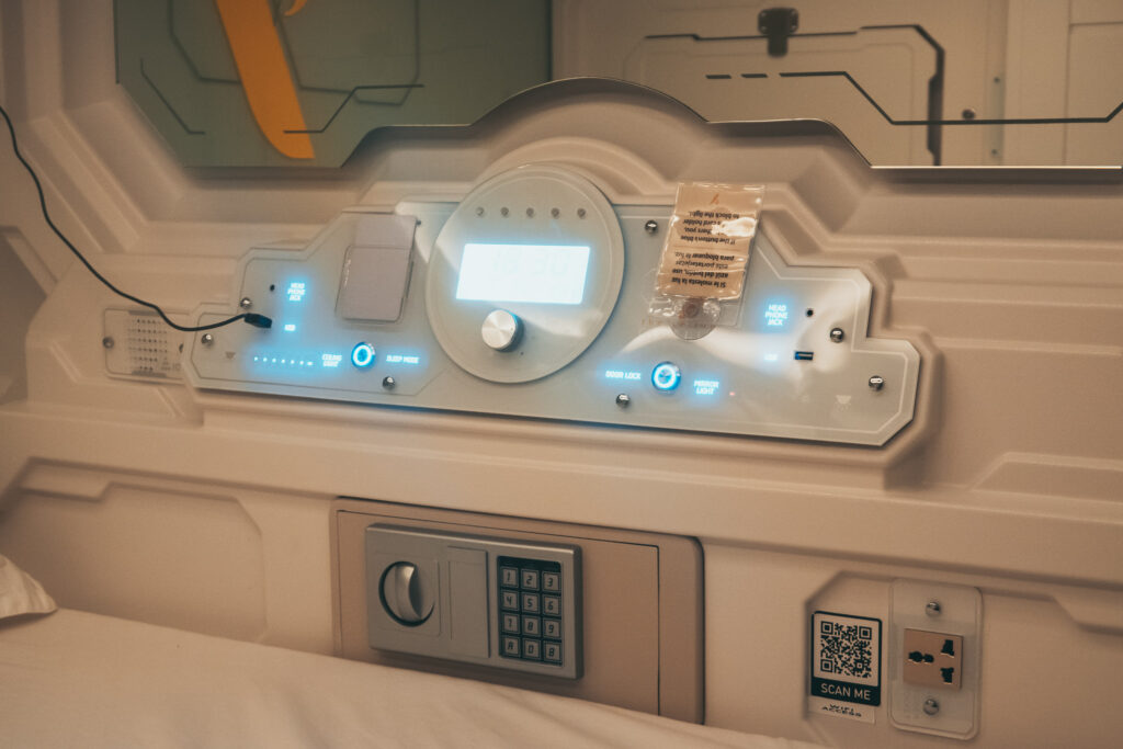 Close-up of the capsule hotel pod control panel with lighting settings, door lock, and in-pod safe at the Yellow Capsule Cancun