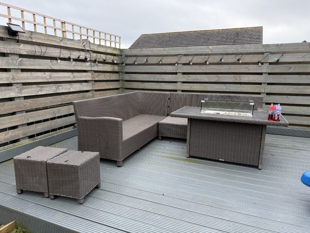 A worn out deck with bare rattan sofa turning green