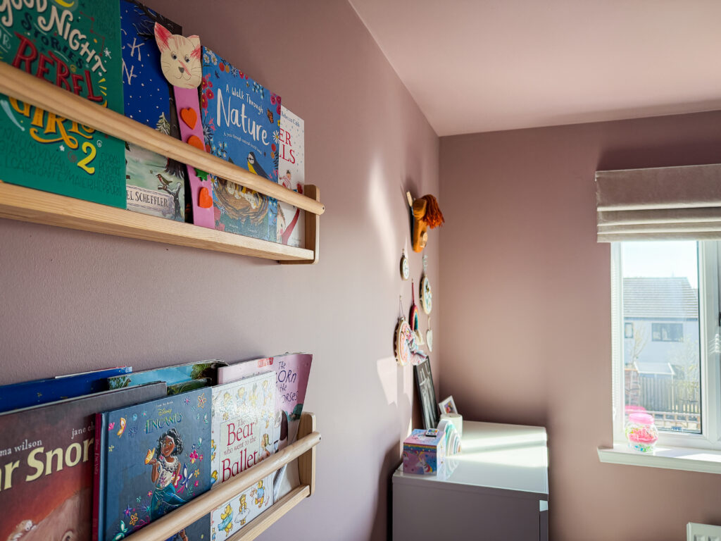 children's book ledges on a farrow and ball sulking room pink wall with view towards gallery wall corner