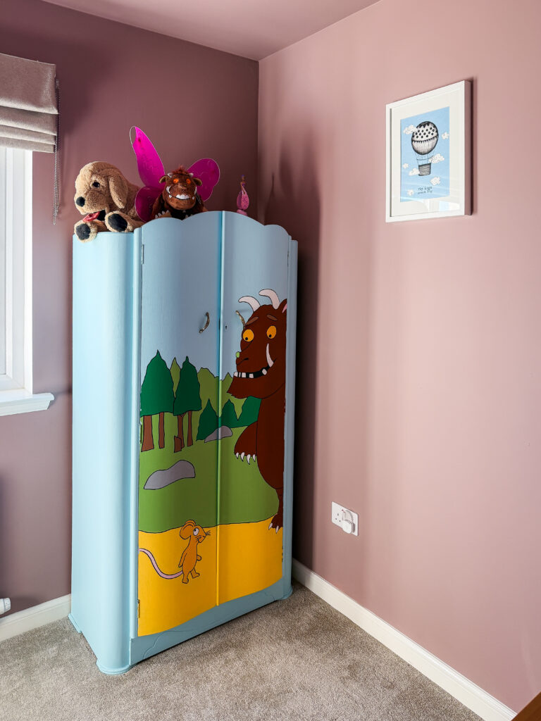 hand painted children's Gruffalo wardrobe in a corner of a bedroom with farrow and ball sulking room pink walls and hot air balloon print