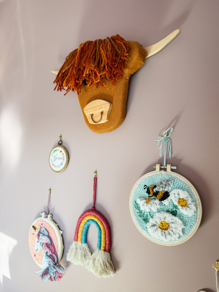 close up of farrow and ball sulking room pink paint colour showing highland cow wall hanging and embroidery hoops