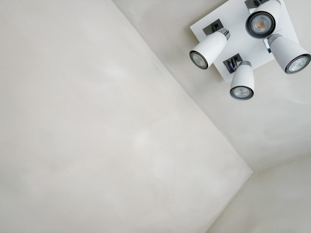 close-up of the faux limewash paint texture where the wall meets the ceiling with a modern spotlight fitting