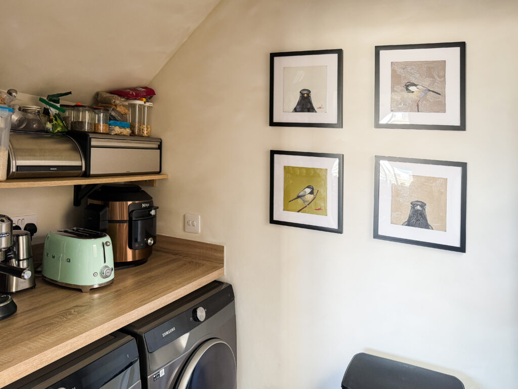 wide angle of the finished utility room showing faux limewash walls, ceiling angles, bird prints, and appliances